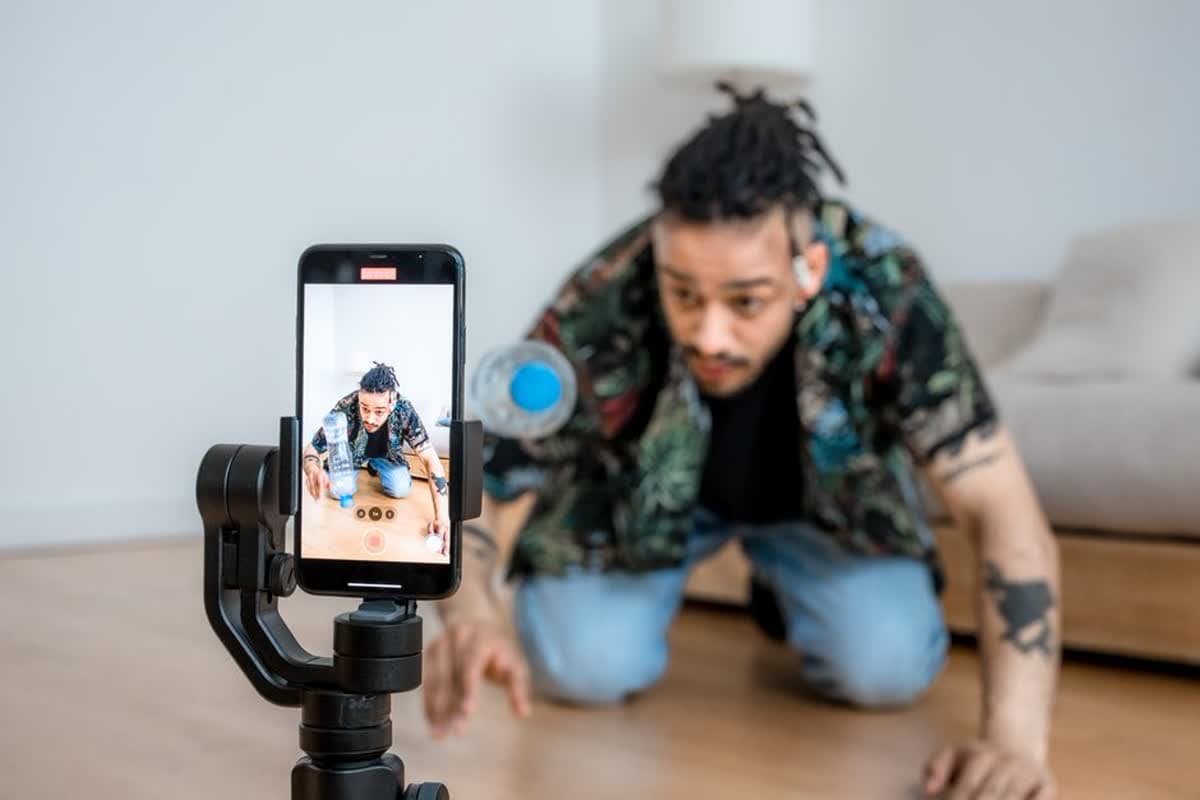 A creator filming video content on a smartphone mounted to a gimbal